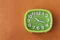 Green clock with white numbers and arrows on orange background Royalty Free Stock Photo