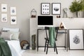 Green cloth on black wooden chair at desk with computer, wooden triangle and cones, real photo with gallery of posters on empty