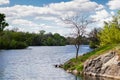 green coast of a beautiful small river with white clouds in reflection Royalty Free Stock Photo