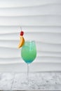 green cocktail in a glass with an orange slice, ice and a cherry on a skewer, an exotic drink Royalty Free Stock Photo