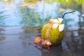 Green coconut with a straw on the edge of a pool