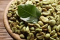 Green coffee beans and leaf in wooden bowl, closeup Royalty Free Stock Photo