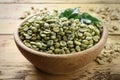 Green coffee beans and leaves in bowl on wooden table, closeup Royalty Free Stock Photo