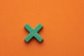 Green color math multiplication sign on orange foamy background