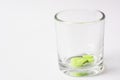 Green color tablet pills in glass on white background