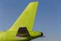 Green colored tail of commercial jet aircraft, blue sky as background. Airplane`s fuselage. Aviation and transportation. Isolated Royalty Free Stock Photo