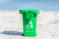Green colored trash can with paper, plastic, glass and organic waste suitable for recycling on sandy beach. Segregate waste