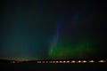 A green colour geomagnetic Aurora borealis on the starry night sky over a city. Aurora Borealis over Swedish lake Islands.