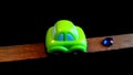 Green colour toy car ,wooden stick and diamond with black background.