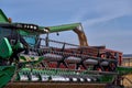 Green combine harvester machine unloading sorghum into a red trailer truck. sorghum harvest in summer. Sunny blue sky Royalty Free Stock Photo