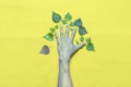 Green concept. Hand with leaves in the form of a tree on a yellow background. One leaf withered and fell from a tree Royalty Free Stock Photo