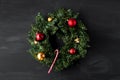 Green coniferous Christmas wreath decorated with red and yellow Christmas balls with bells and one candy can in the center on a bl Royalty Free Stock Photo