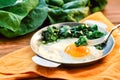 Green cooked spinach with fried egg on iron pan plate. Fried eggs healthy breakfast eating on wooden table background served by