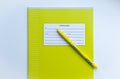 Top view of front page of green pupils copybook with form to sign in name, surname, grade, etc. with yellow pen on white backgro