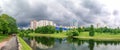 A green corner of tranquility with trees, grass, pond, located among urban residential areas on an overcast day