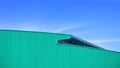 Green Corrugated metal curved Roof of large Warehouse Building in modern style against blue sky Background Royalty Free Stock Photo