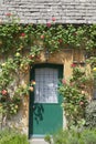 Green cottage doors surrounded by climbing red roses