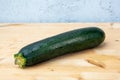 Green courgette on wooden table with grey background