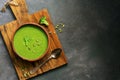 Green cream broccoli soup with pumpkin seeds in a ceramic bowl on a cutting board, dark rustic background. Top view. Vegetarian Royalty Free Stock Photo