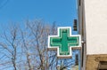 Green cross pharmacy sign or symbol on the building facade view from the street Royalty Free Stock Photo