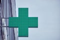 Green cross of a pharmacy store on the wall of a building, copy space Royalty Free Stock Photo