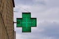 green cross-shaped pharmacy sign with sky in the background Royalty Free Stock Photo