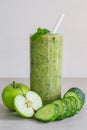 Green cucumber and apple smoothie in a glass, sliced ingredients