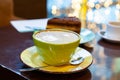 Close up and selected focus view on mug of coffee on brown wooden table. Hot coffee with latte art served with piece of orange- Royalty Free Stock Photo