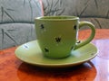 A green cup sits on a green saucer on the table