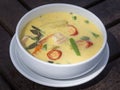 Green curry creamy soup with coconut milk, shrimp, red pepper, bean in white bowl, Thai cuisine