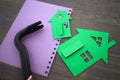 Green cutouts of model houses with hand tool on a notepad Royalty Free Stock Photo