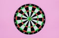 Green dart arrow hitting in the target center of dartboard, metaphor to target success, winner concept, on pink pastel background Royalty Free Stock Photo