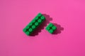 Green details cubes of children`s constructor on a pink background