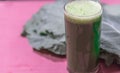 Green detox juice from cabbage leaves on pink background