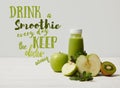 green detox smoothie with apples, kiwi and mint and on white wooden surface, drink smoothie everyday keep doctor away inscription Royalty Free Stock Photo