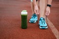 Green detox smoothie cup and woman lacing running shoes before w Royalty Free Stock Photo