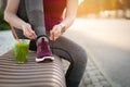 Green detox smoothie cup and woman lacing shoes before workout