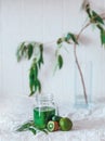 Green detox smoothie spinach. Bright color cucumber lime kiwi fruits and grass. White textile selected focus. Glass jar Royalty Free Stock Photo