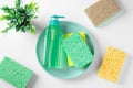 Green dishwashing detergent on blue dish with cleaning sponge and on white background
