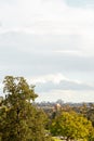 Green dissiduous trees in park with city skyline and cloudy sky Royalty Free Stock Photo