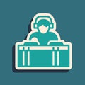 Green DJ wearing headphones in front of record decks icon isolated on green background. DJ playing music. Long shadow