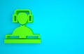 Green DJ wearing headphones in front of record decks icon isolated on blue background. DJ playing music. Minimalism