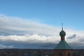 The green dome of the church with a cross against the evening blue sky with white clouds and the silhouette of the city Royalty Free Stock Photo