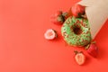 1 green donut, fresh red strawberries , paper bag on a red