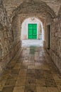 Green door at the end of the stone tunnel