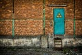 Green door with nuclear sign on brick wall