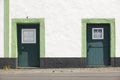 Green doors over a white facade building and street. Azores Royalty Free Stock Photo