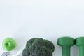 Green dumbbell, fresh broccoli, apple, and glass of water isolated on white background, top view, copy space Royalty Free Stock Photo