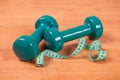 Green dumbell with measuring tape Royalty Free Stock Photo