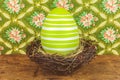 Green dyed big easter egg in a bird nest on a wooden table